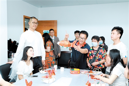 昨日，在新會(huì)區(qū)民政局婚姻登記處，工作人員向剛領(lǐng)證的新人們展示新會(huì)魚燈制作技巧。