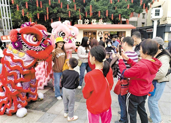 游客在長堤歷史文化街區(qū)與醒獅合影。何雯意