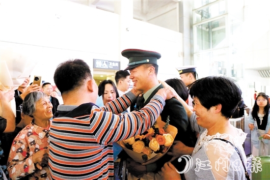 身著軍裝的返鄉(xiāng)退役士兵逐一出站，迎接他們的是鮮花與擁抱。