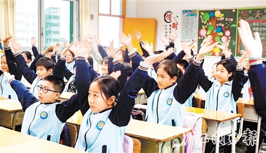 學(xué)生們?cè)谡n桌前跟隨節(jié)奏做起“室內(nèi)課桌操”。