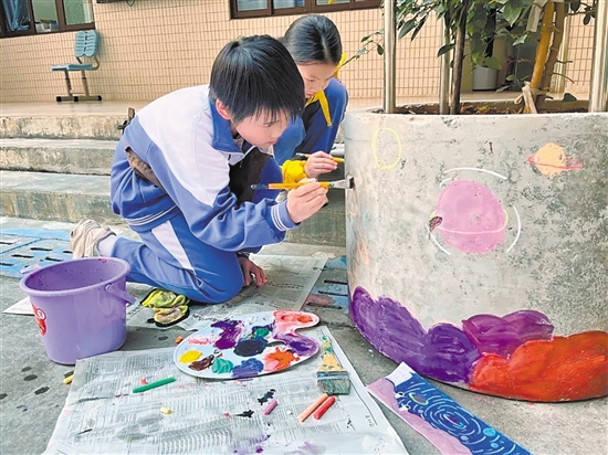 學(xué)生們?cè)谛@內(nèi)的花墩上進(jìn)行精心繪制，為校園風(fēng)景增色添彩。