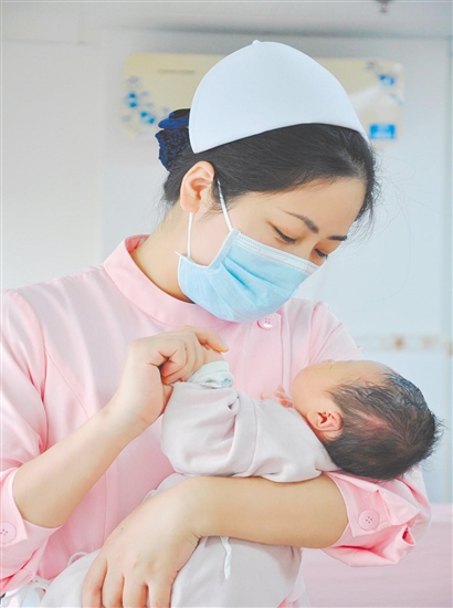 這是一雙托起生命的手。江門市中心醫(yī)院愛嬰?yún)^(qū)主管護師湯玲玲正在安撫哭鬧的寶寶。她一手環(huán)住襁褓，一手牽起寶寶的小手，動作舒緩而溫柔。在這里，生命的啼哭與溫柔的守護相遇，匯聚成世間至暖的力量。（林錦棠