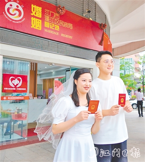 一對新人在蓬江區(qū)民政局婚姻登記處門口合影留念。
