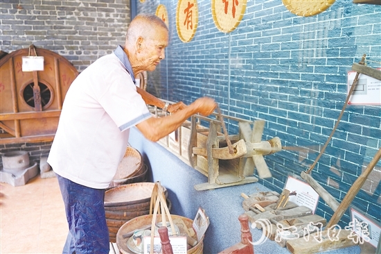 新華村打造農(nóng)耕文化展館，留住鄉(xiāng)村記憶。圖為村中老人向記者介紹農(nóng)具。