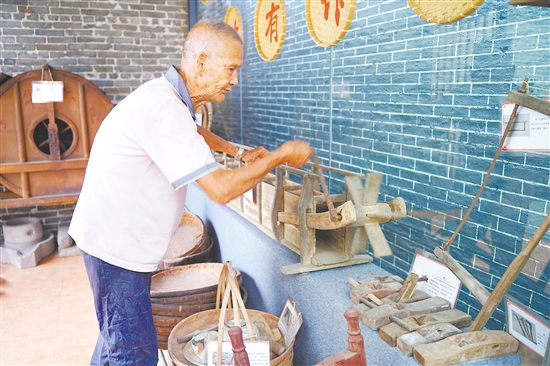 新華村打造農(nóng)耕文化展館，留住鄉(xiāng)村記憶。圖為村中老人向記者介紹農(nóng)具。