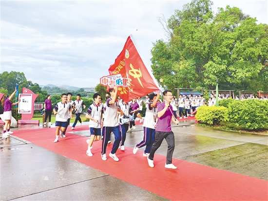 在臺(tái)山市武溪中學(xué)，老師揮舞著“中考加油”的紅旗為考生加油助威。