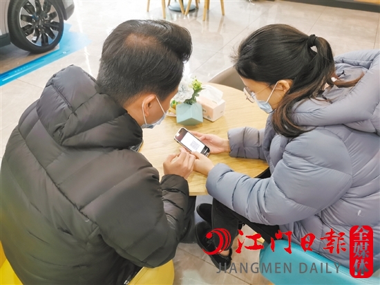 新能源汽車銷售人員協(xié)助車主用手機(jī)進(jìn)行投保新能源汽車險(xiǎn)。